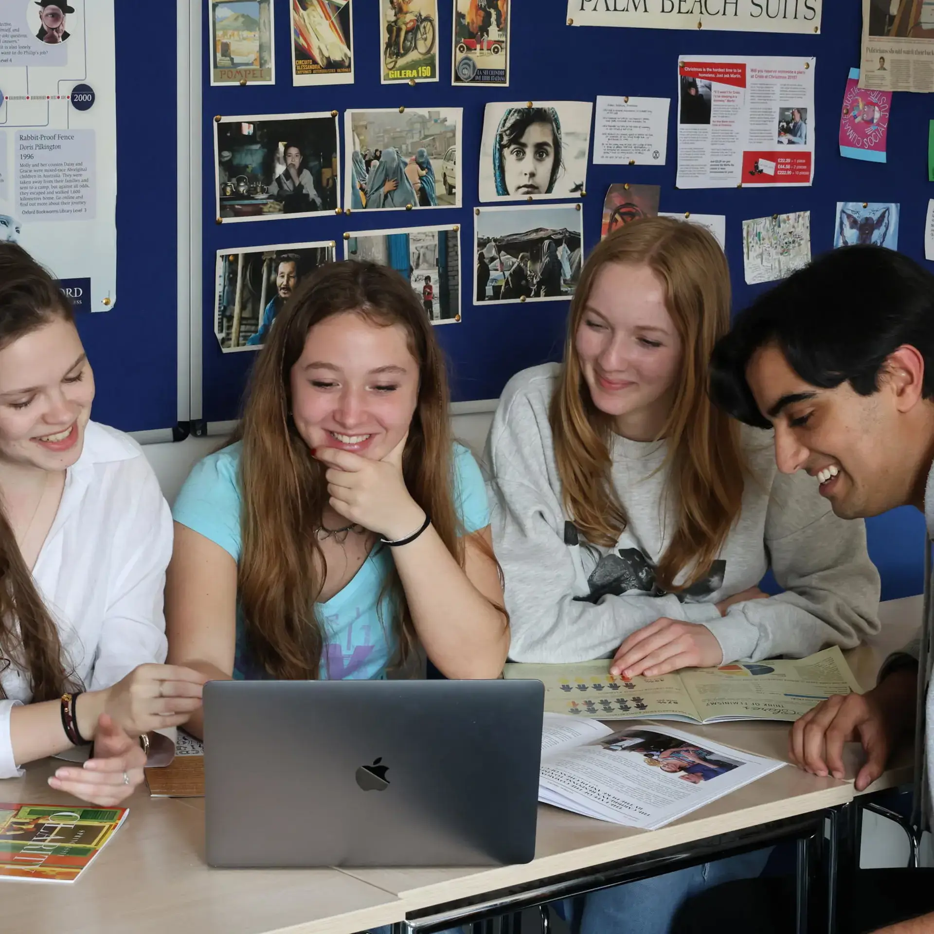 Four students working collaboratively on laptop