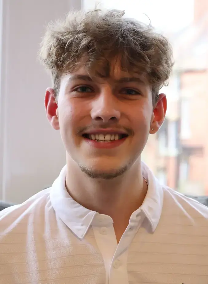 Male student wearing a white shirt and smiling