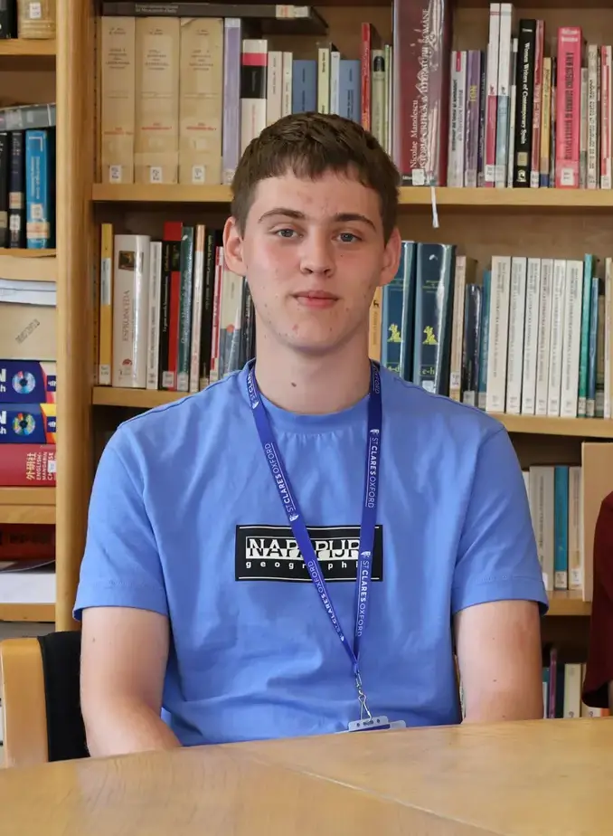 Male student wearing light blue shirt sat in library
