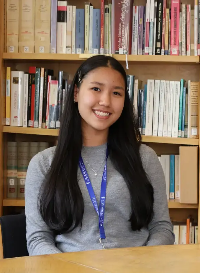 Female student in grey cardigan sat in library