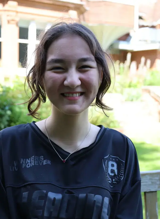 Female student wearing dark blue shirt sat on garden bench