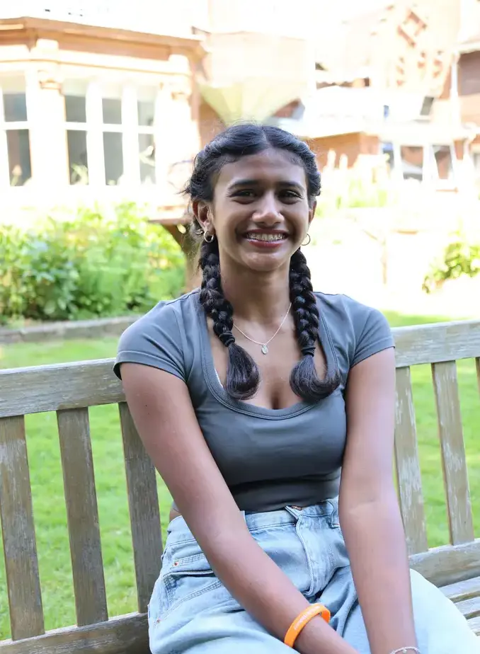 Female student wearing grey shirt sat on garden bench
