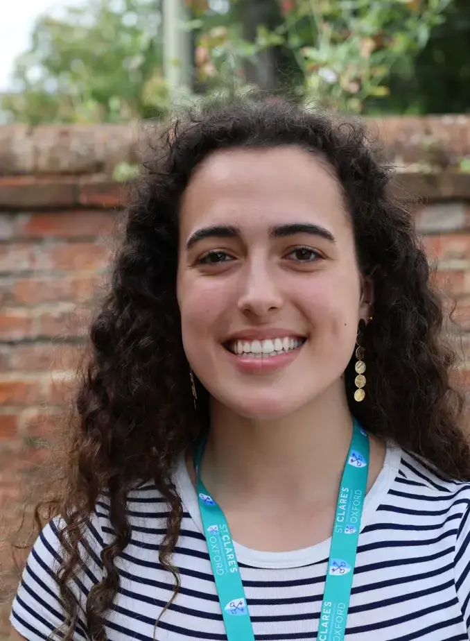 Female student wearing a striped shirt with brick wall behind her