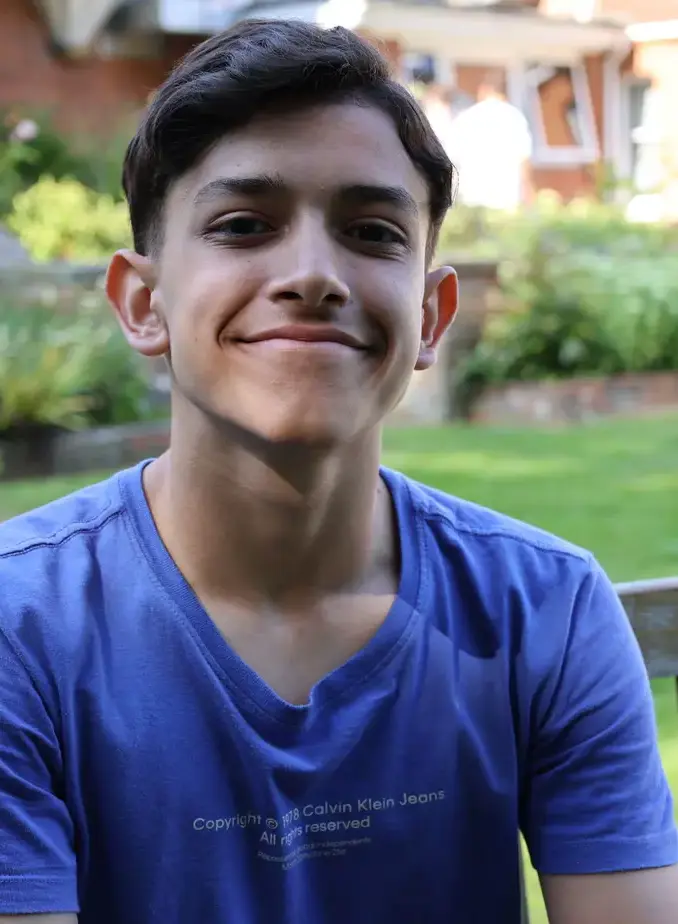 Male student wearing blue shirt sat on garden bench
