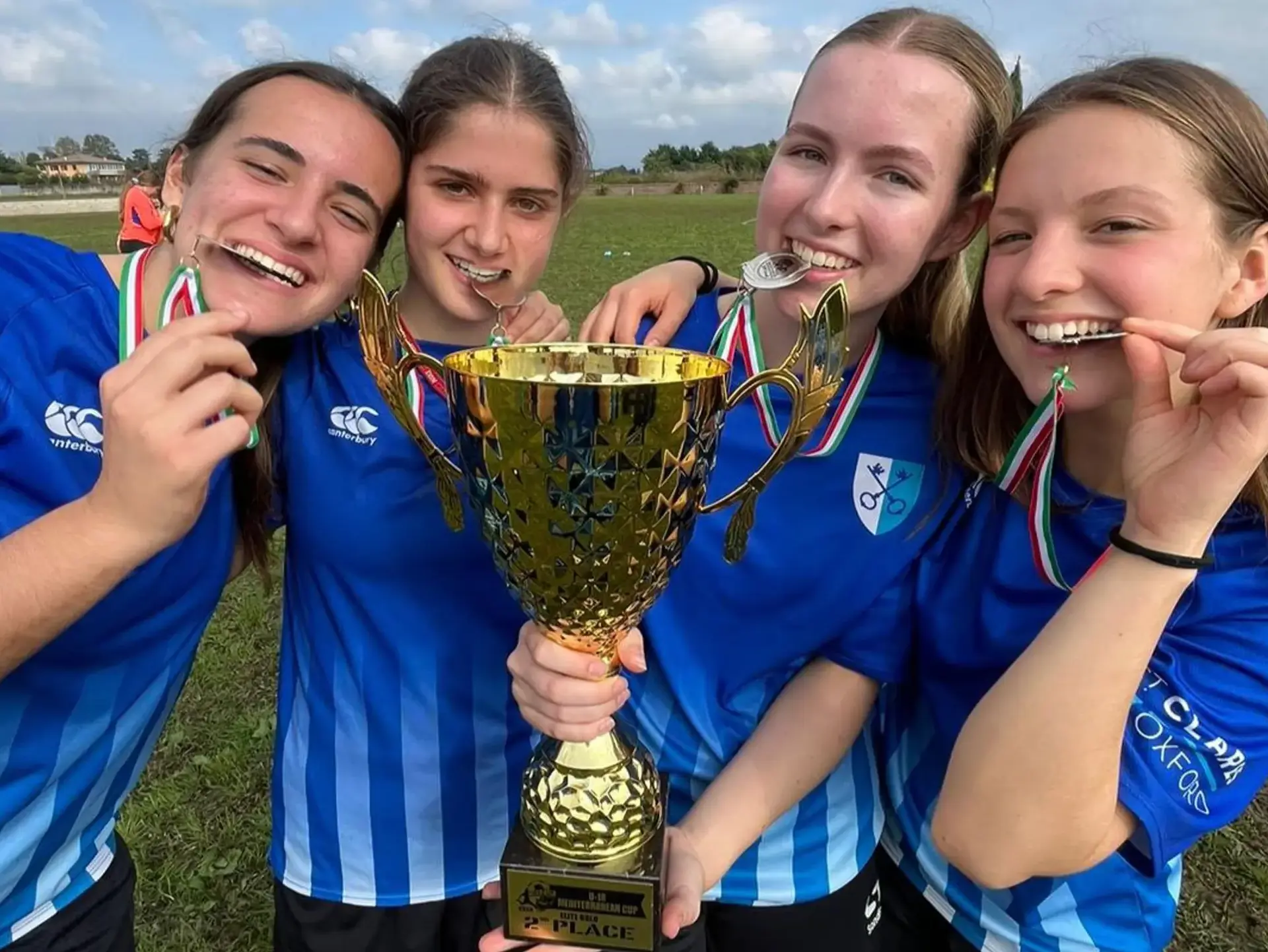 Student athletes holding trophy and chewing medals