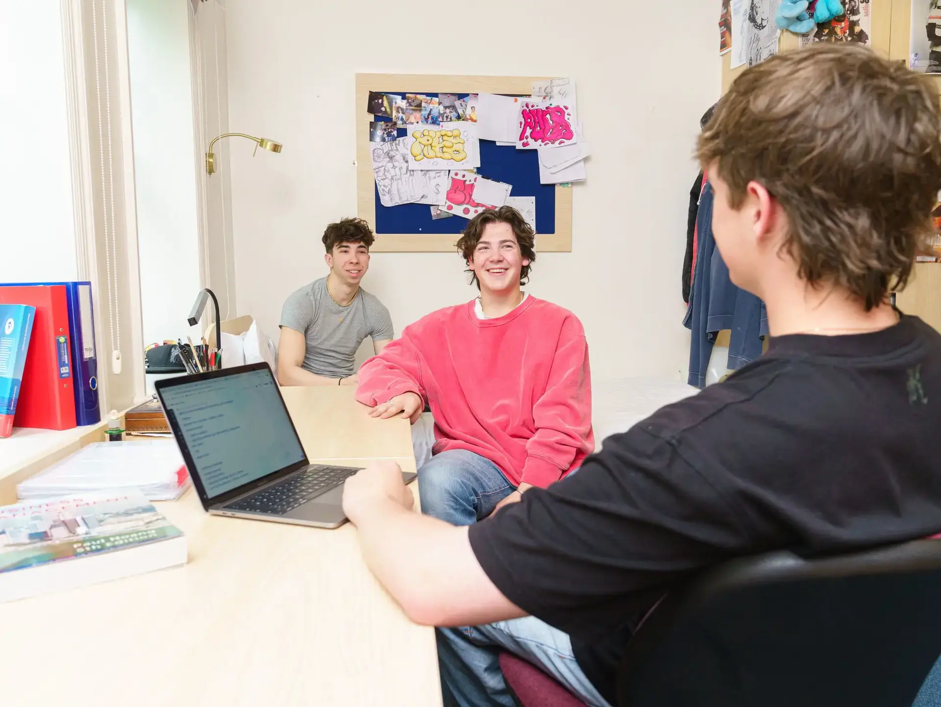 Three students sitting at desk in bedroom