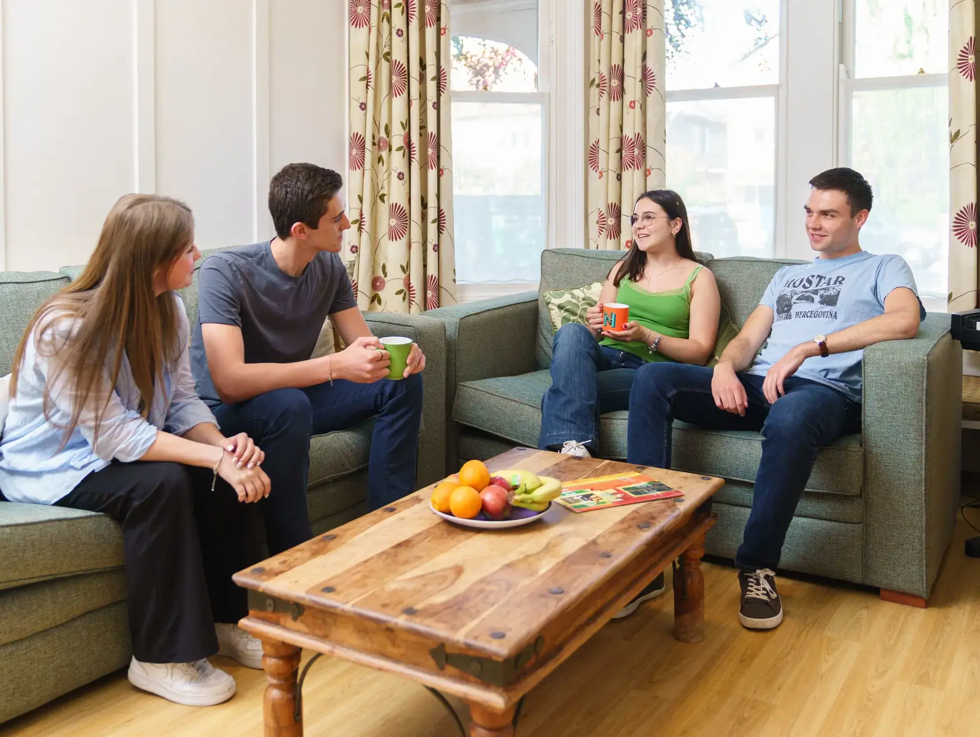 Four students chatting on common room sofas