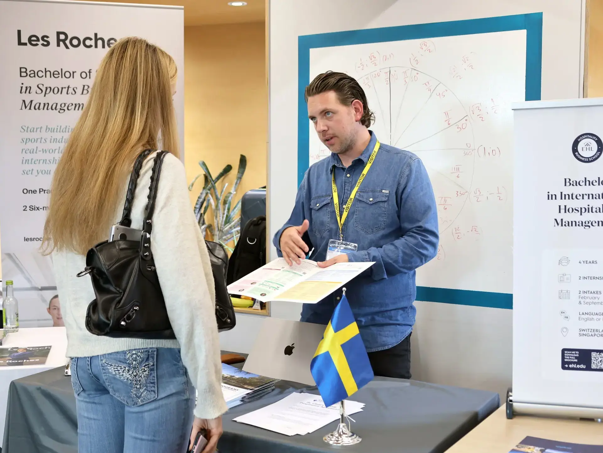 Teacher showing student open book at careers fair