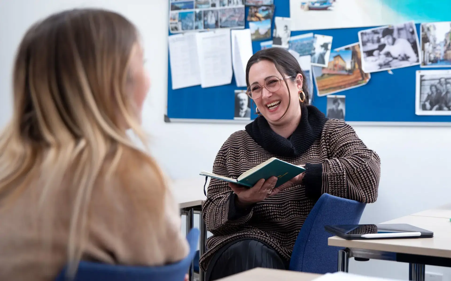 Student laughing as they read from book