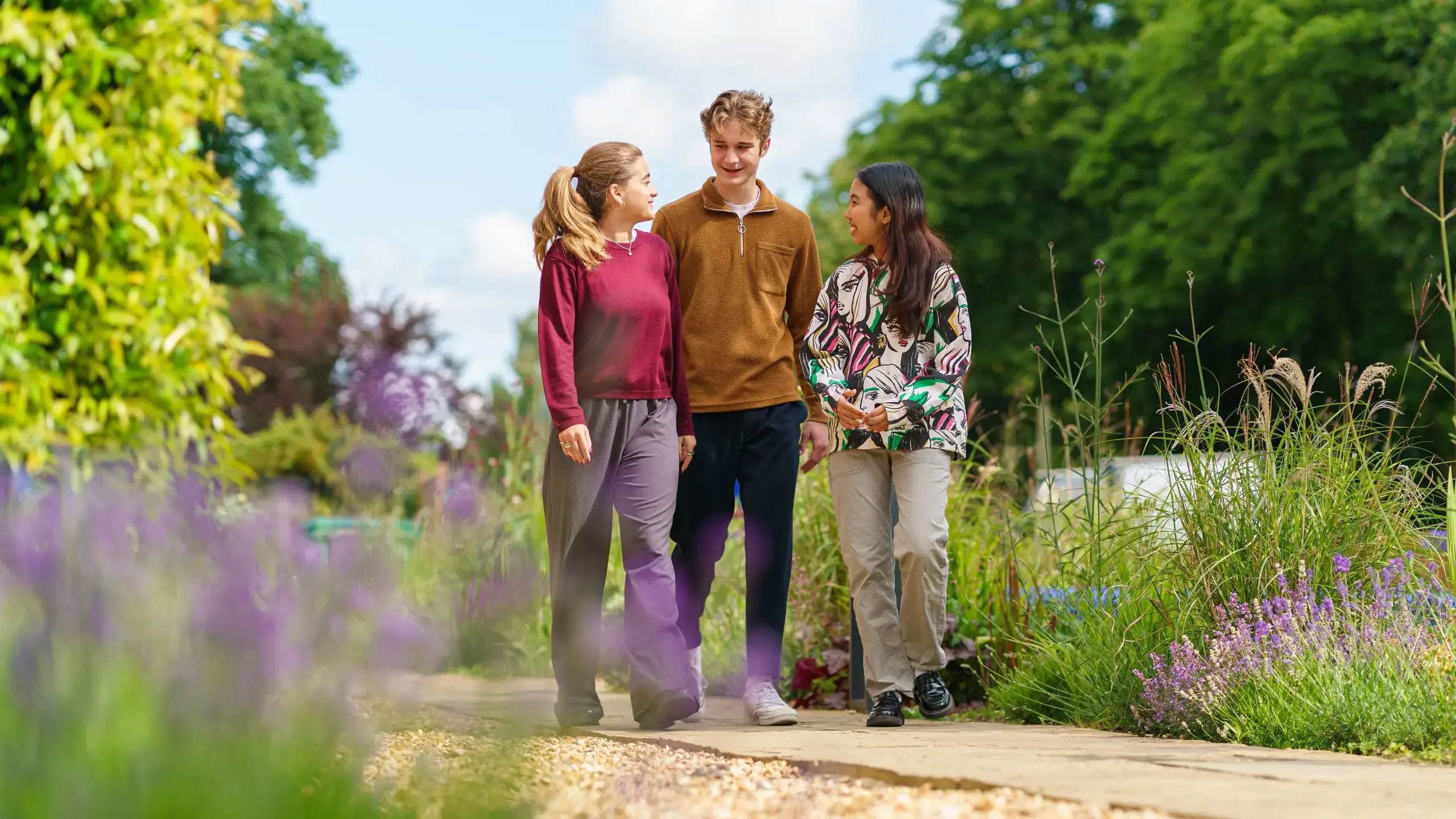 Three students walking along path in meadow