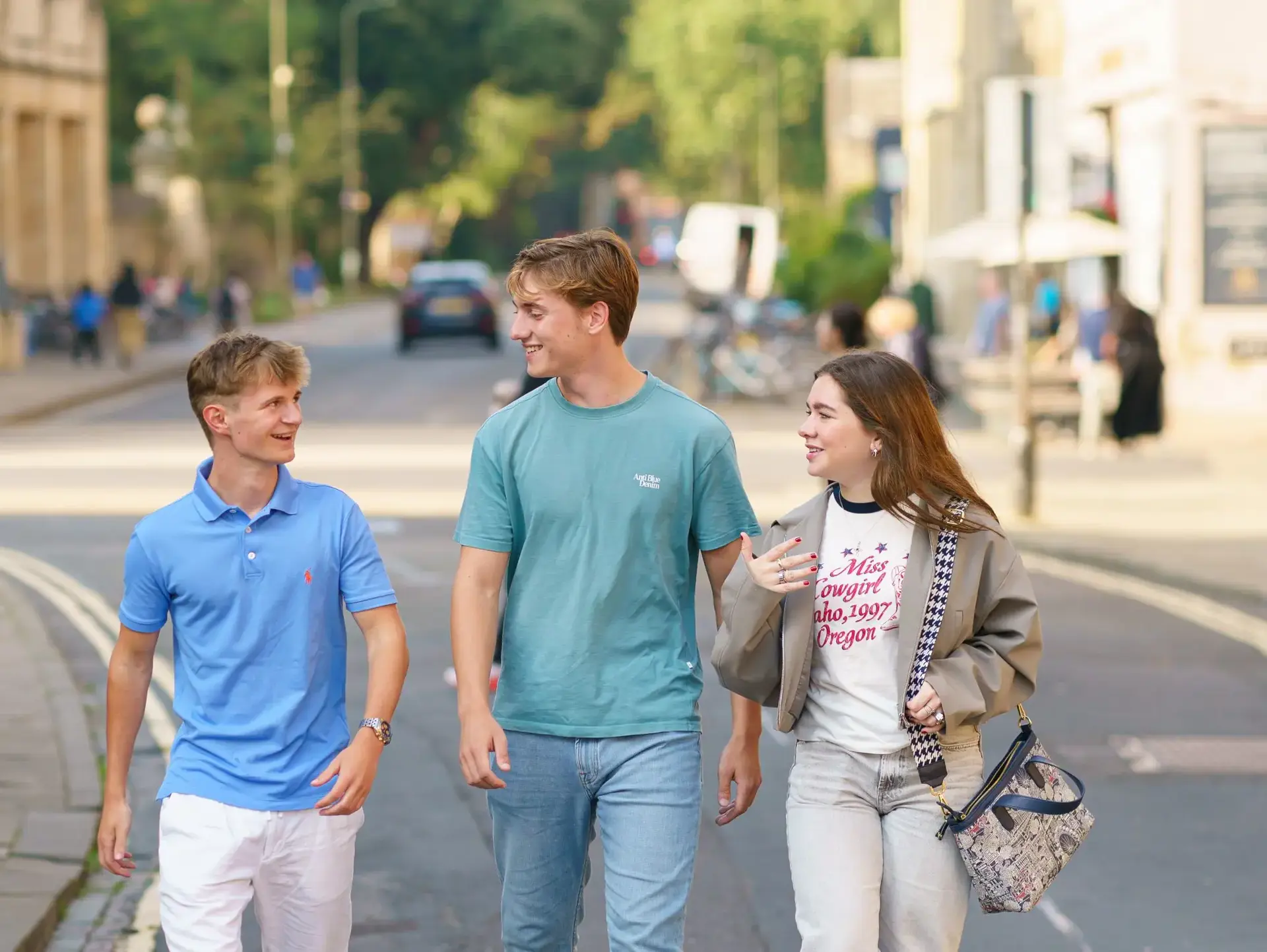 Three students walking down street on sunny day