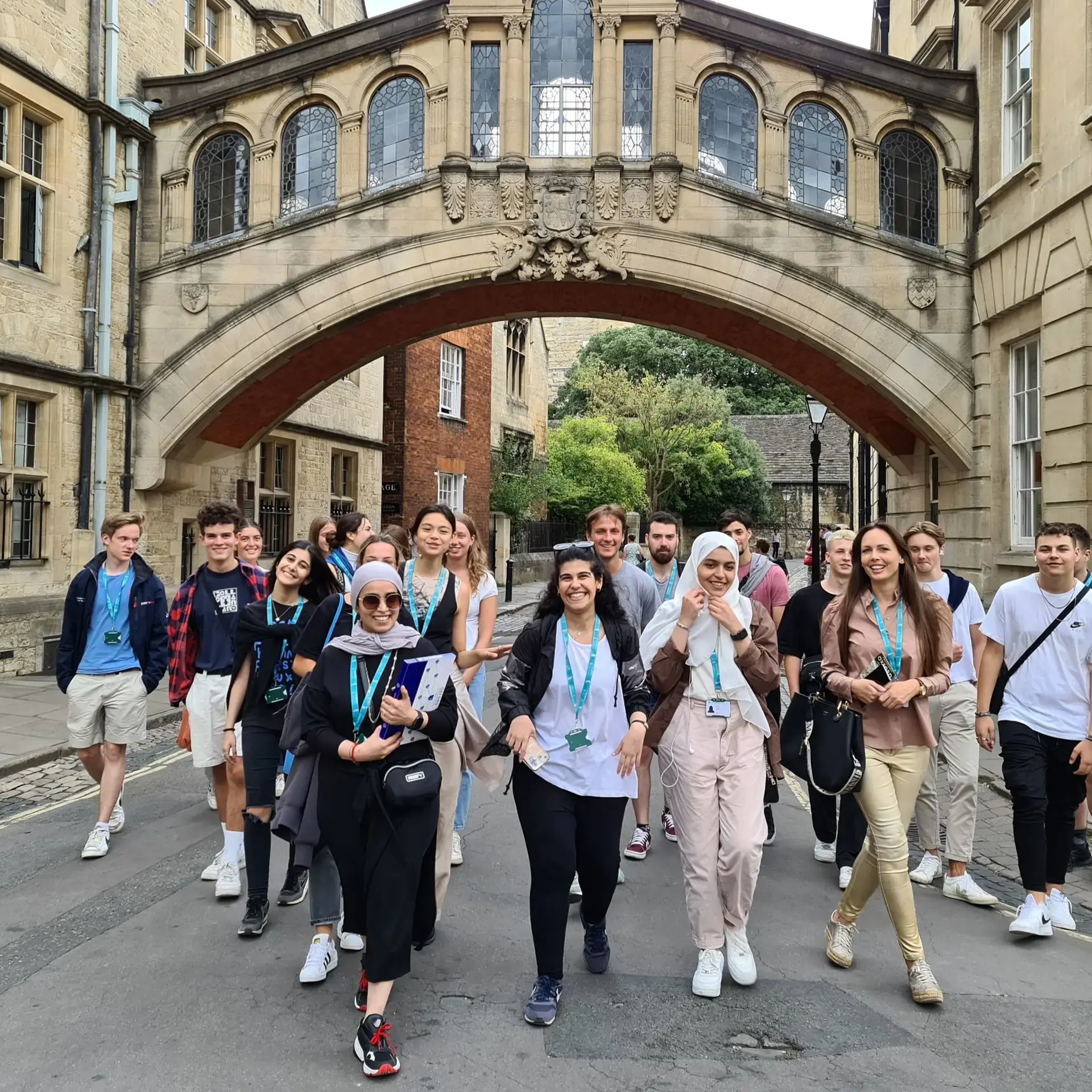 Students wearing lanyards walking under skybridge arch