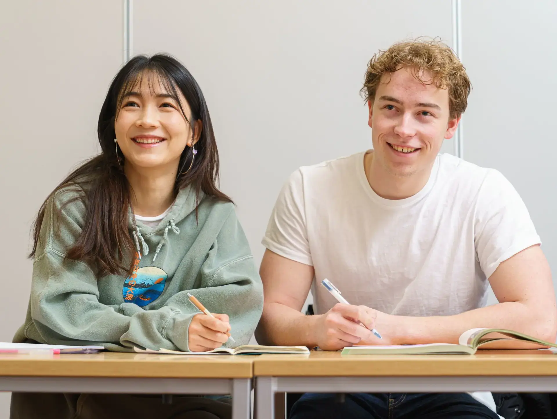 Two students smiling up from their desks