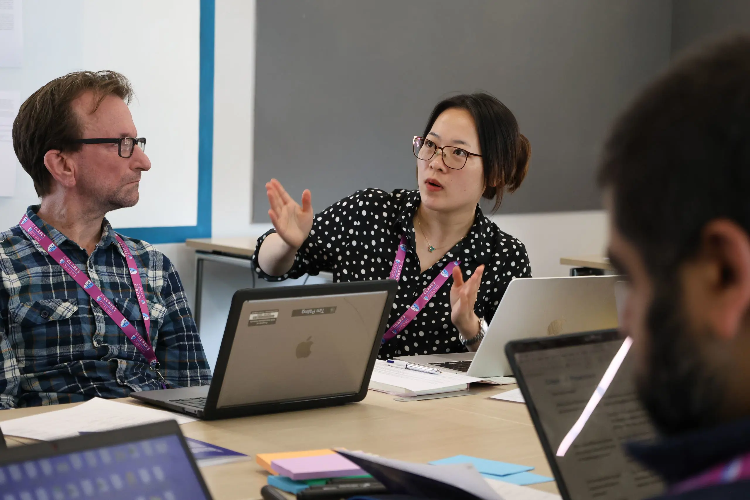 Teachers conversing in class about course with laptops