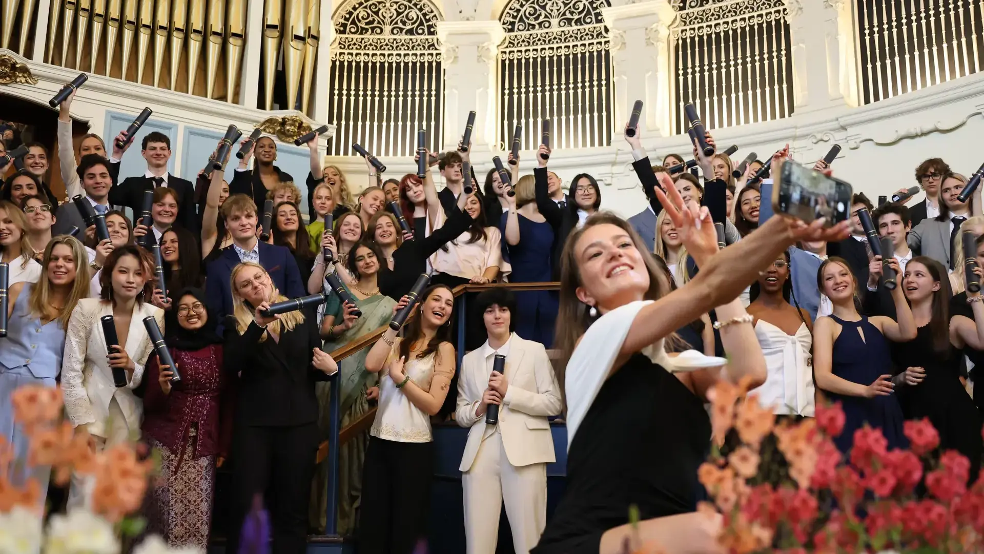 Graduating students celebrating, holding diplomas