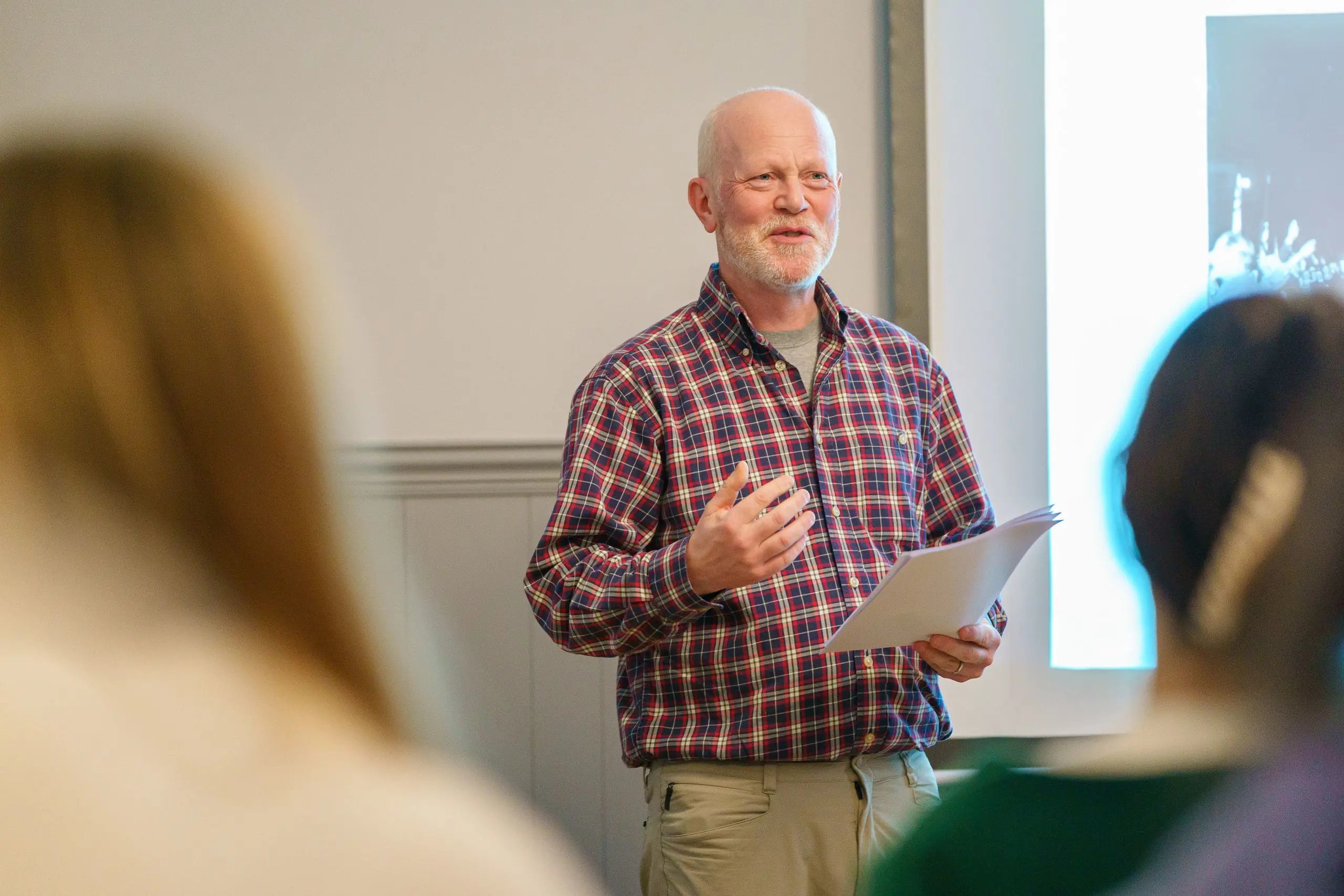 Teacher reading from notepad at front of classroom