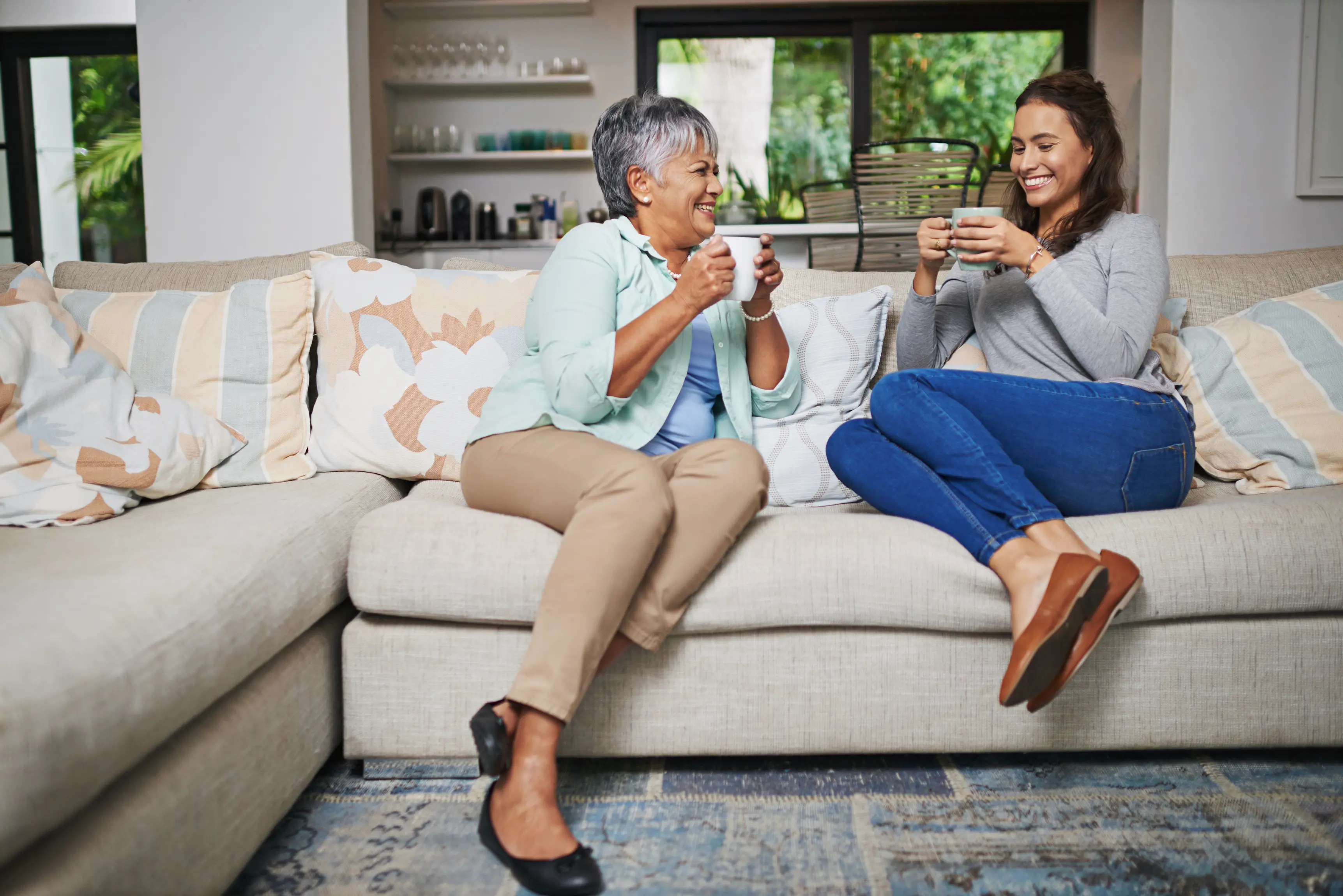Homestay parent and student drinking coffee on sofa and smiling together