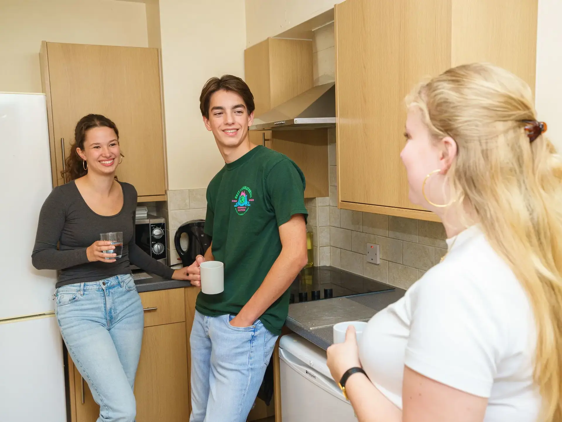 Three students chatting in kitchen