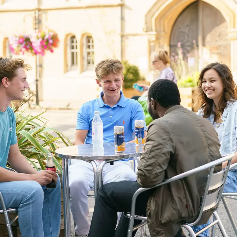 Students sat at table in Oxford talking and smiling