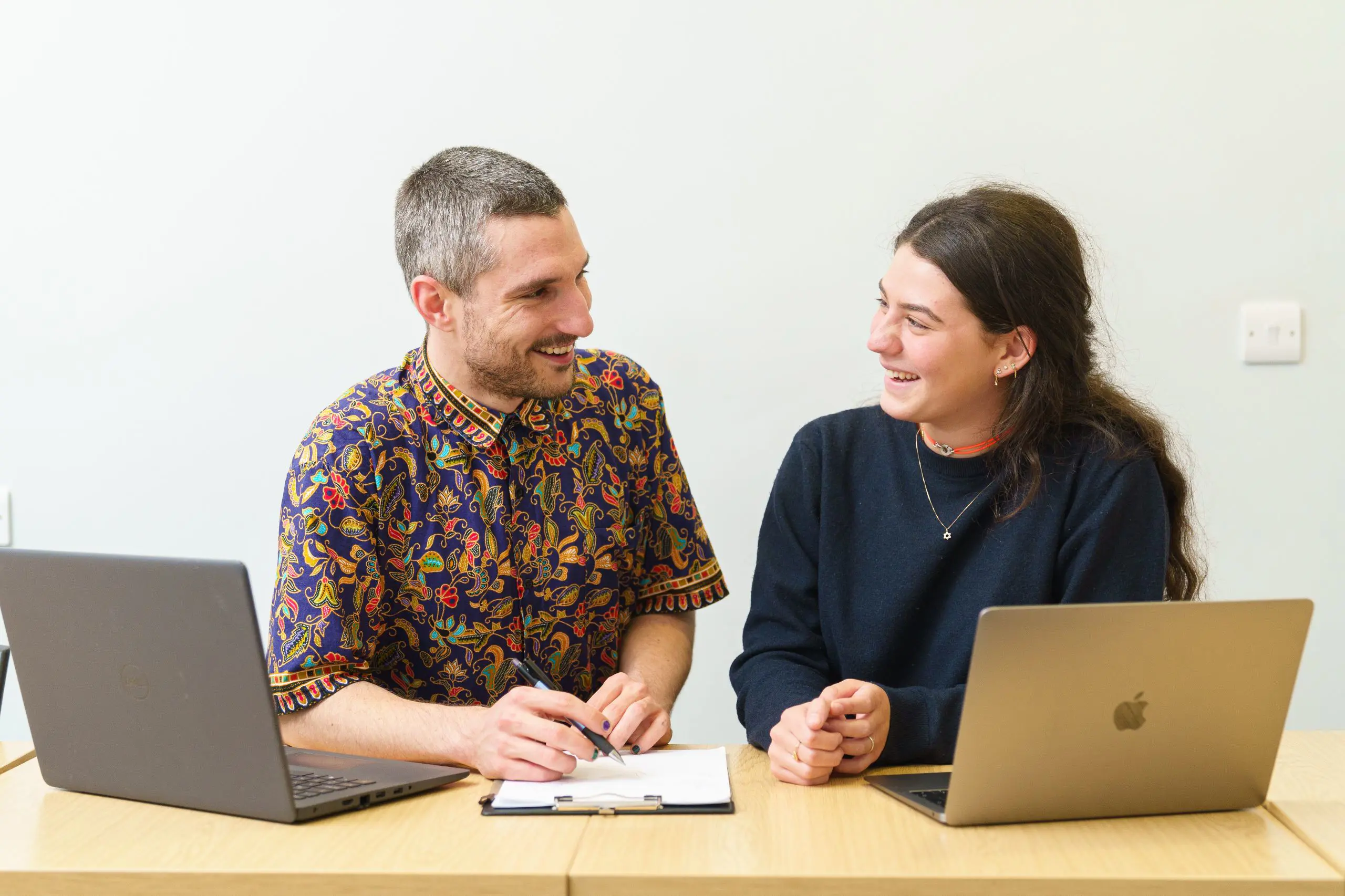 Student and teacher chatting while teacher writes on clipboard