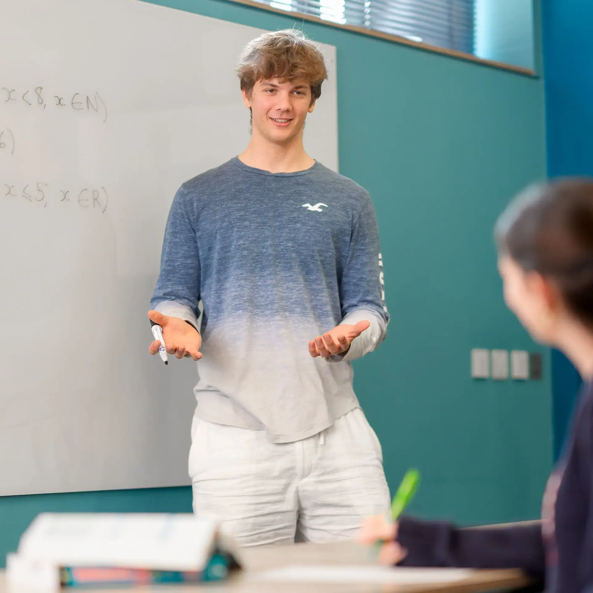 Peer mentor explaining concept to student in classroom
