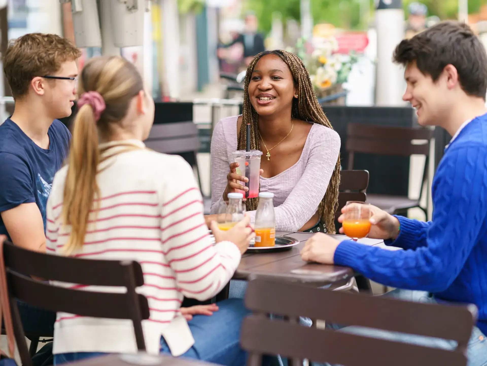 Four students sitting outdoors at a cafe