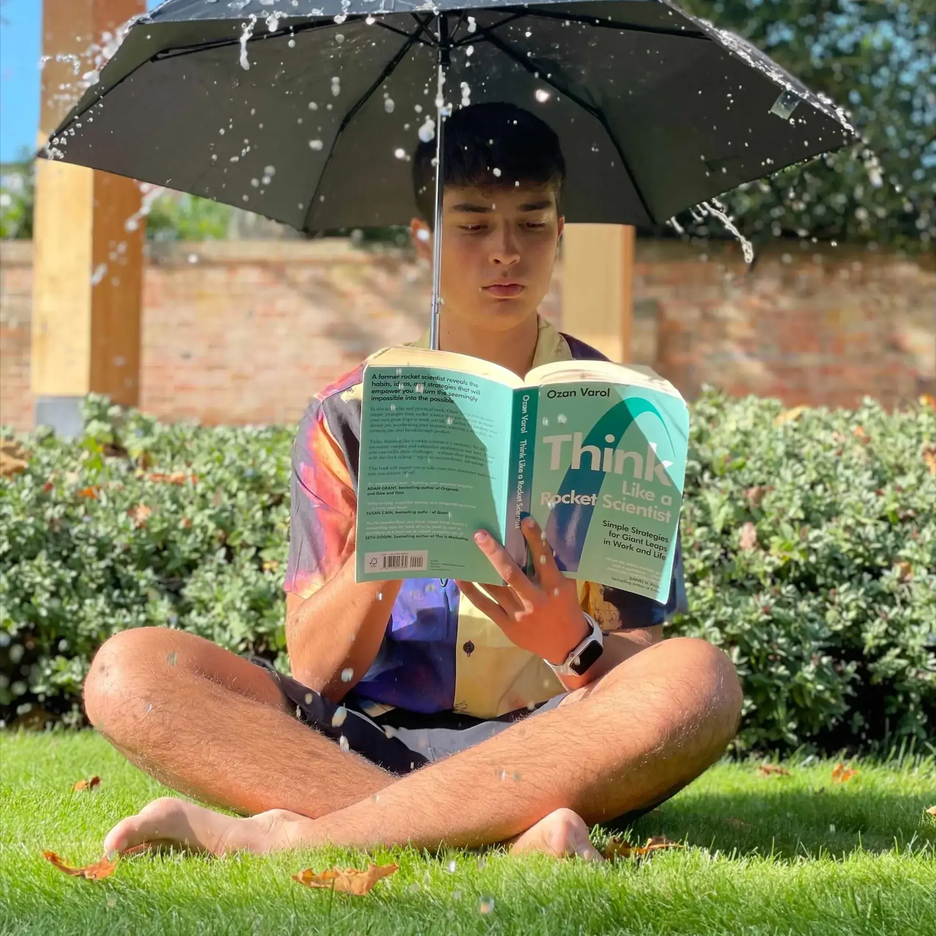 Student reading under umbrella 