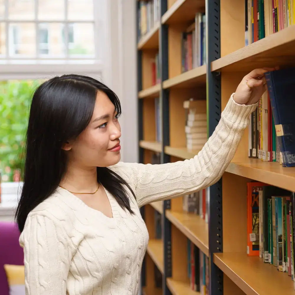 Student selecting book from bookshelf in library