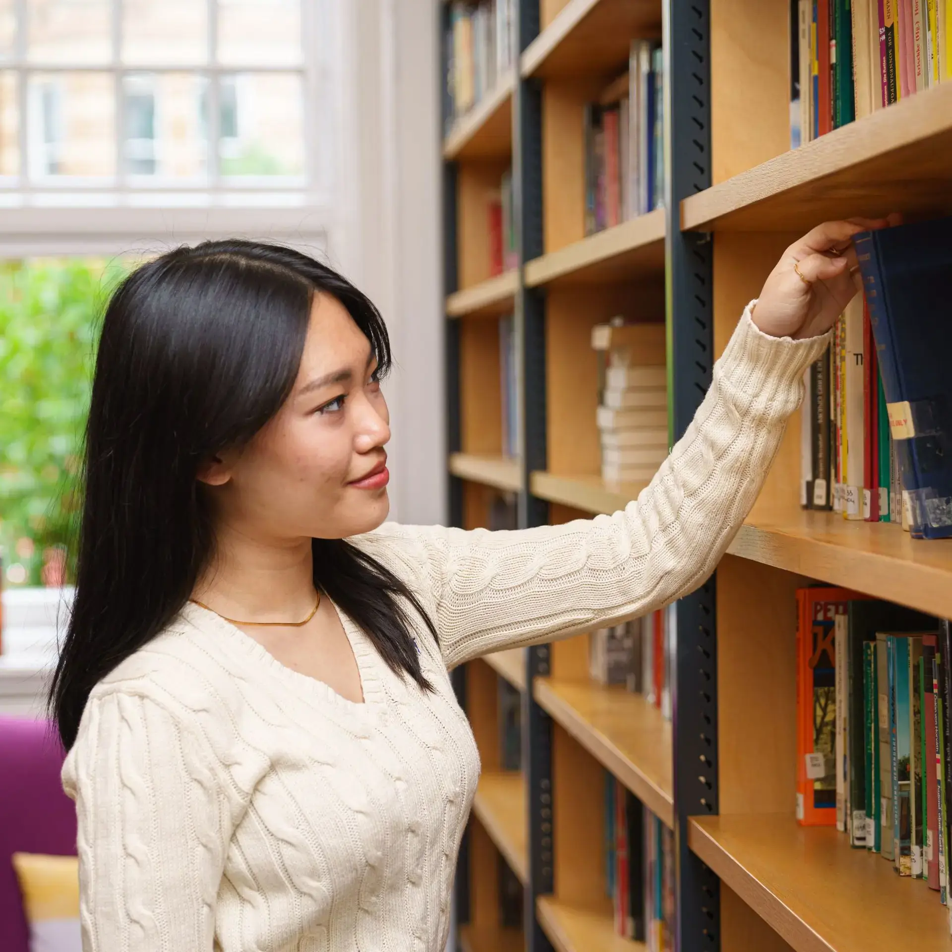 Student picking book off library shelf