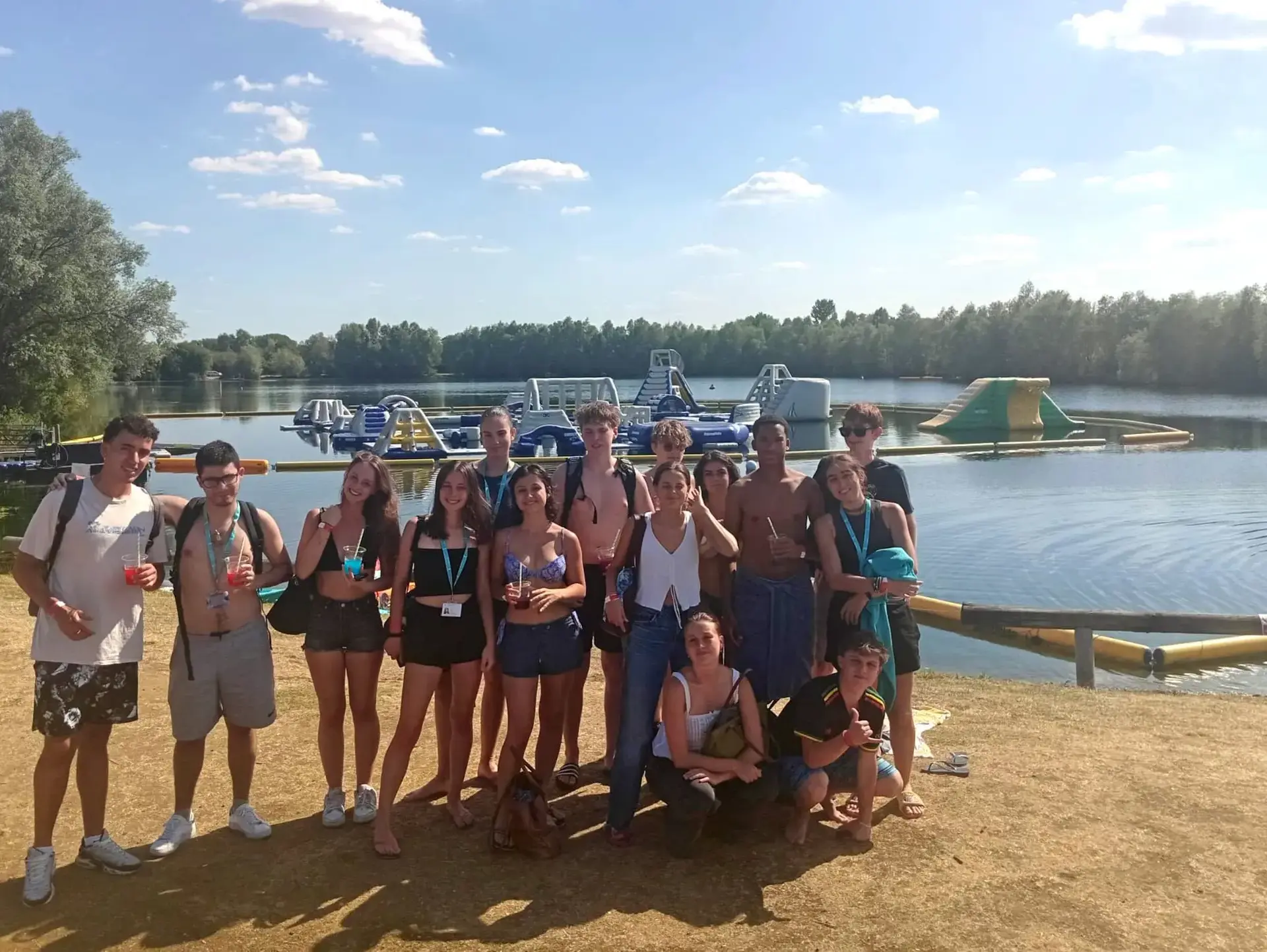 Students standing on bank of river, with large inflatables in the water