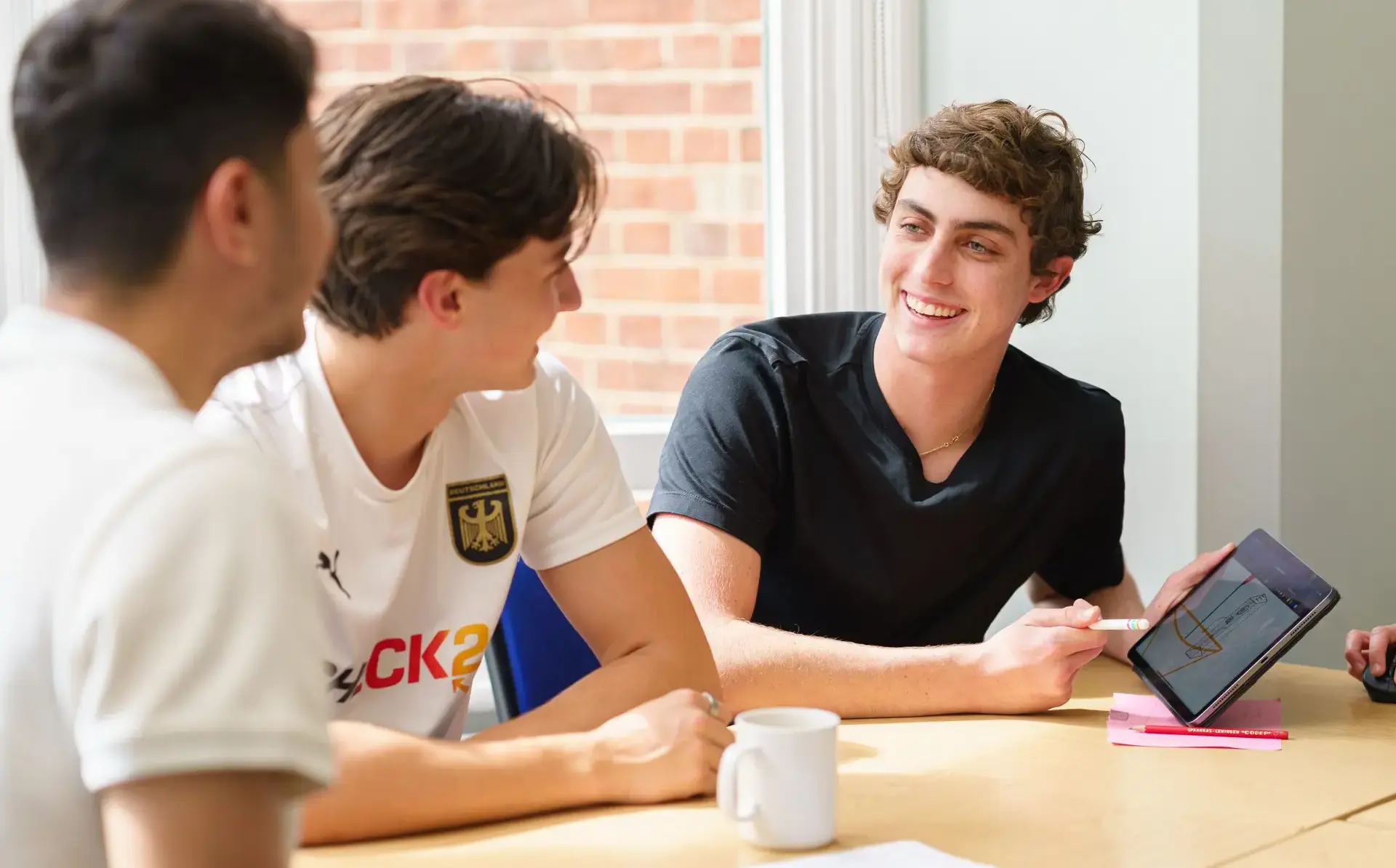 Student showing two classmates content on tablet