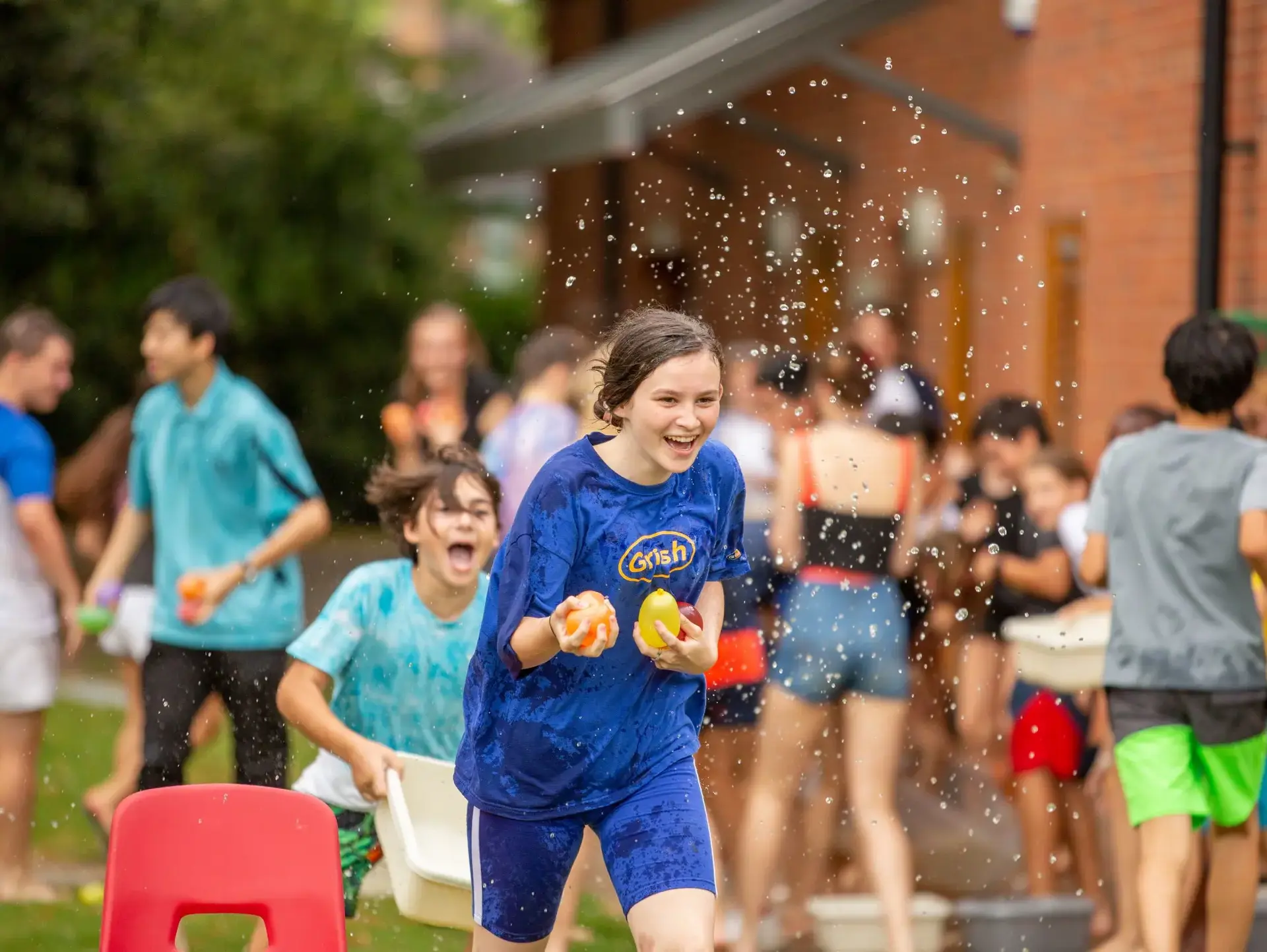 Student running, holding two water balloons