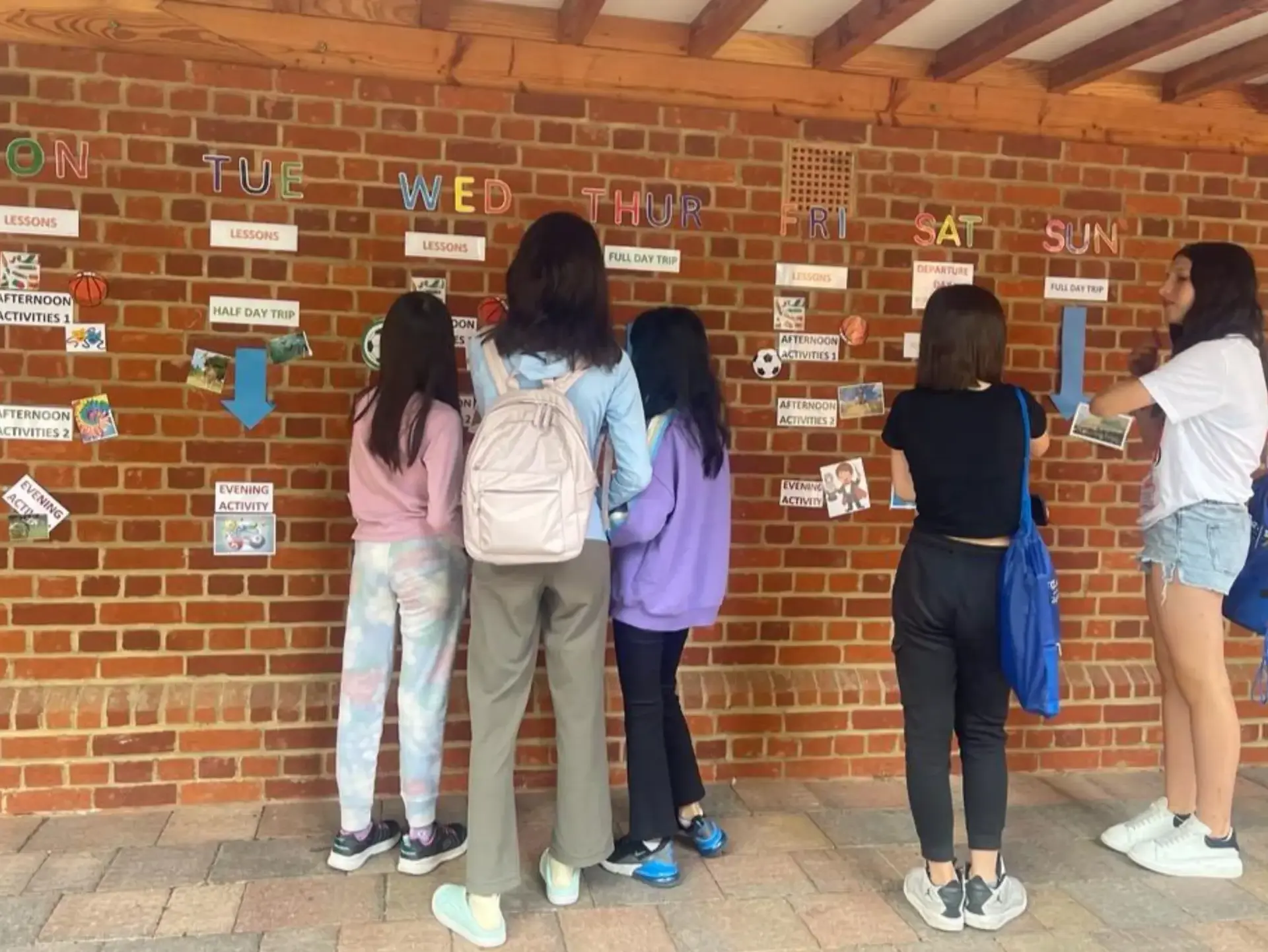 Students looking at timetable set across brick wall