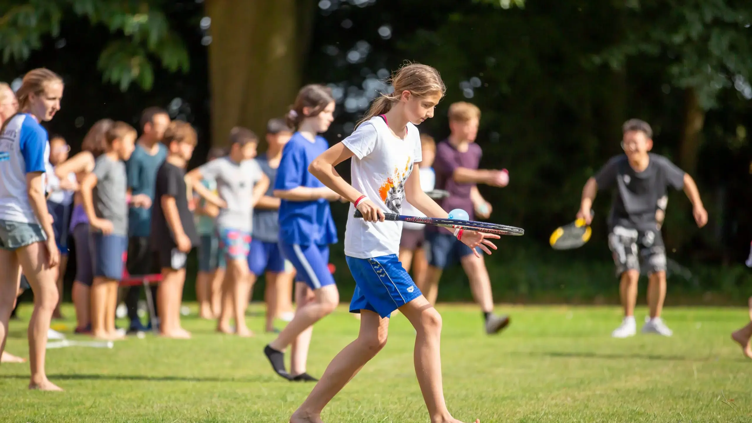 Student balancing water balloon on badminton bat