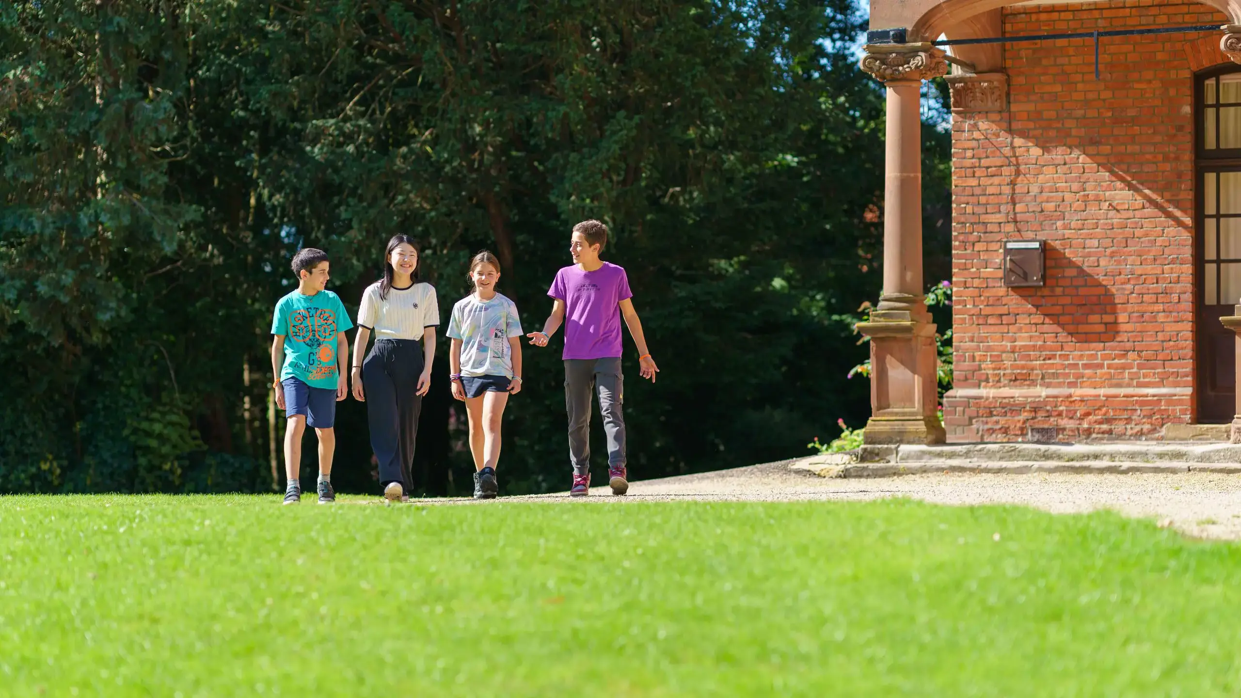 Four students walking across lawn