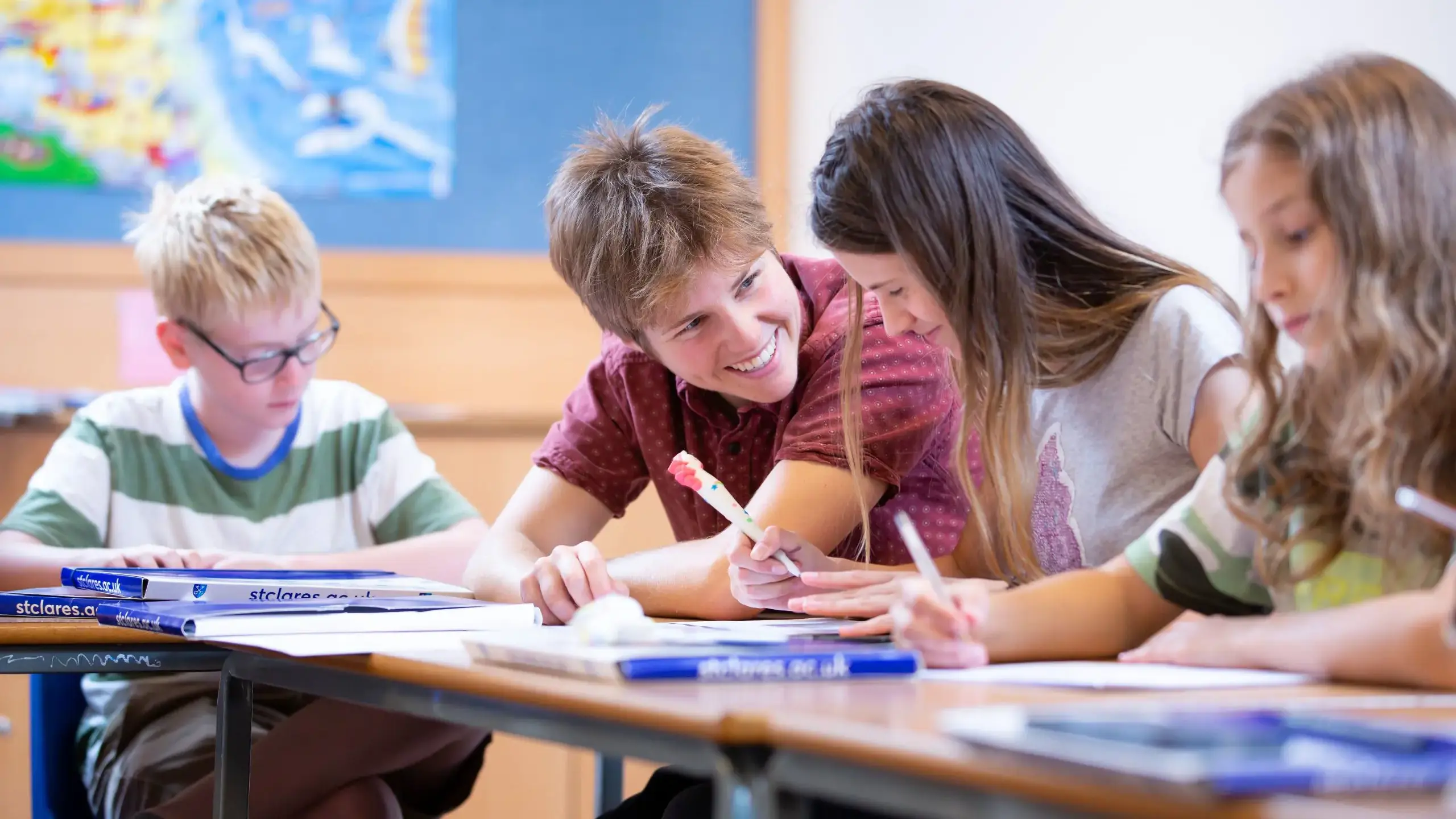 Students smiling, writing at desks