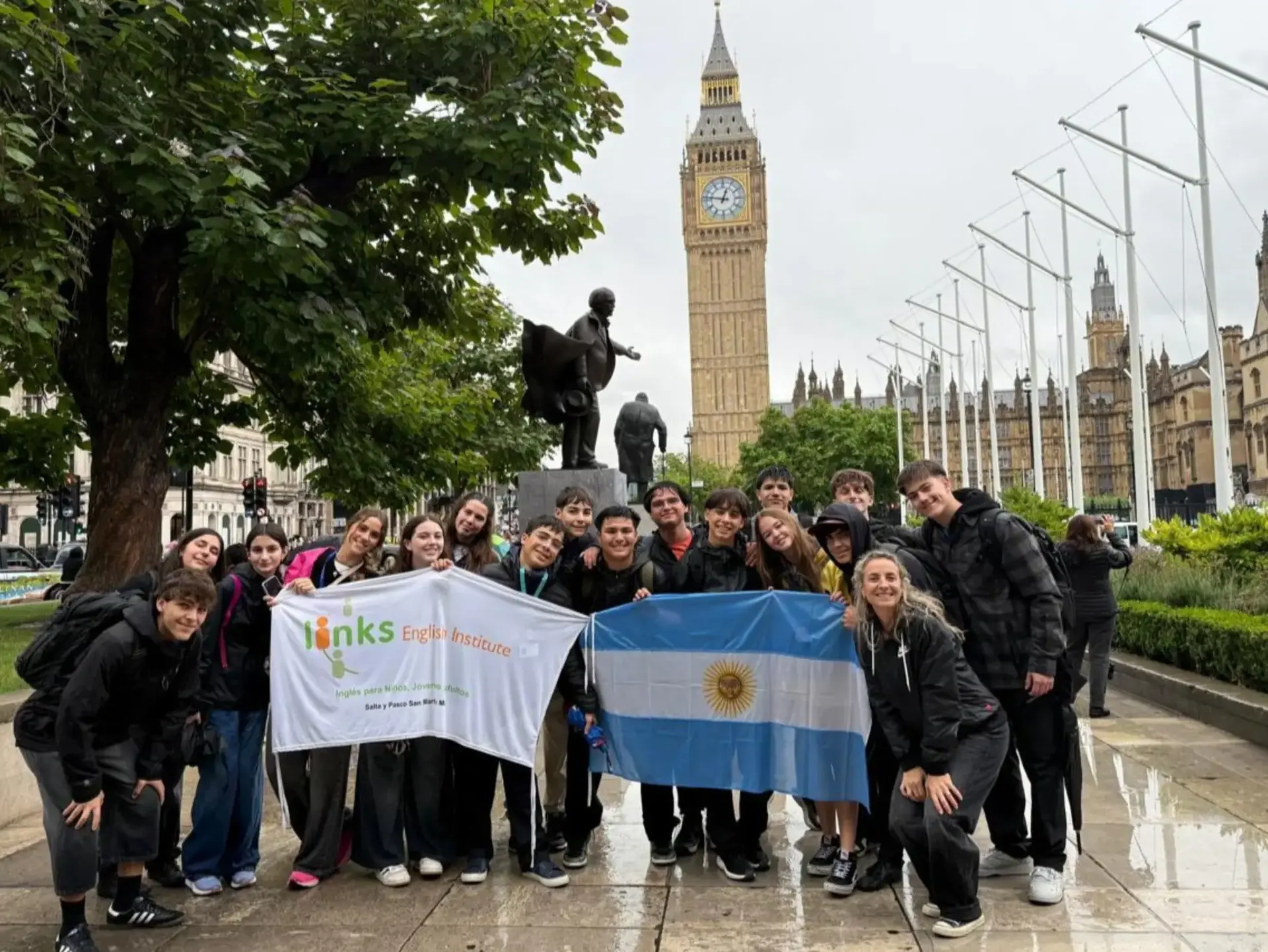 Students posing outside Big Ben, holding a banner and an Argentine flag