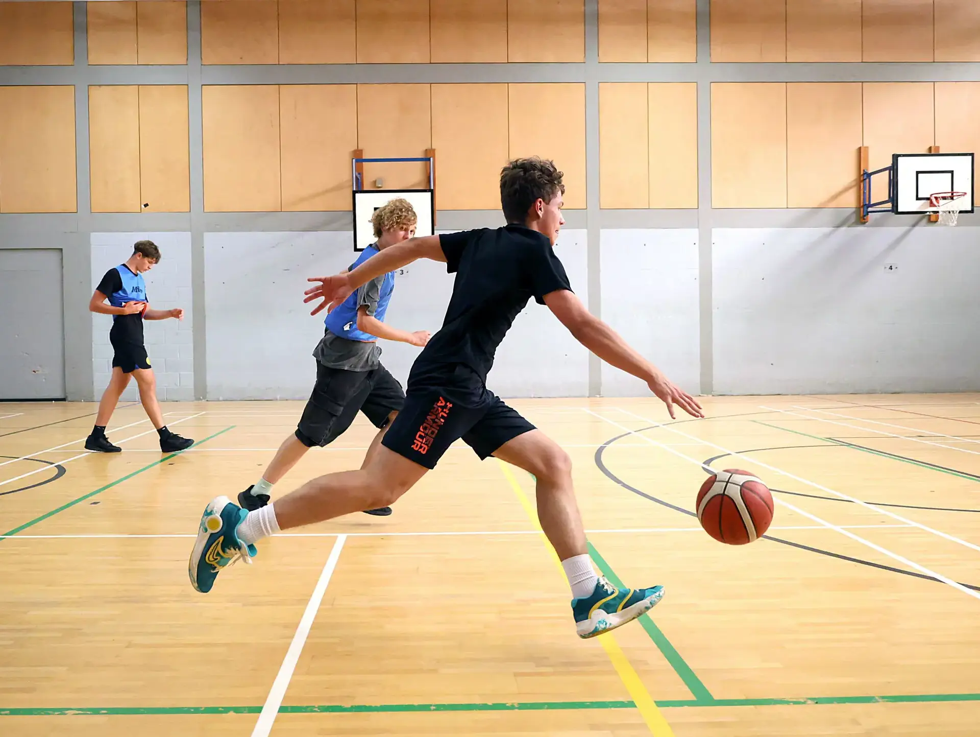 Students playing basketball on indoor court