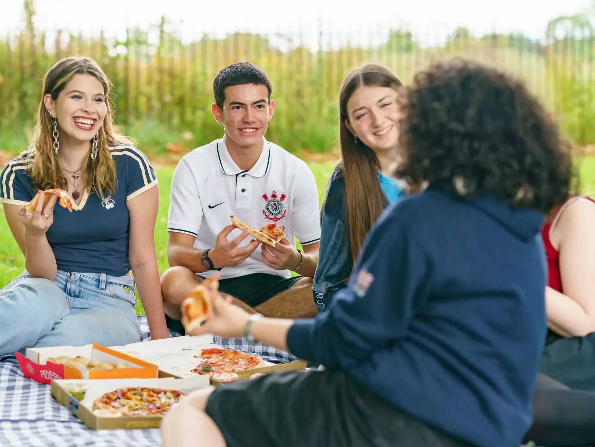 Students sitting on picnic blanket, sharing pizza