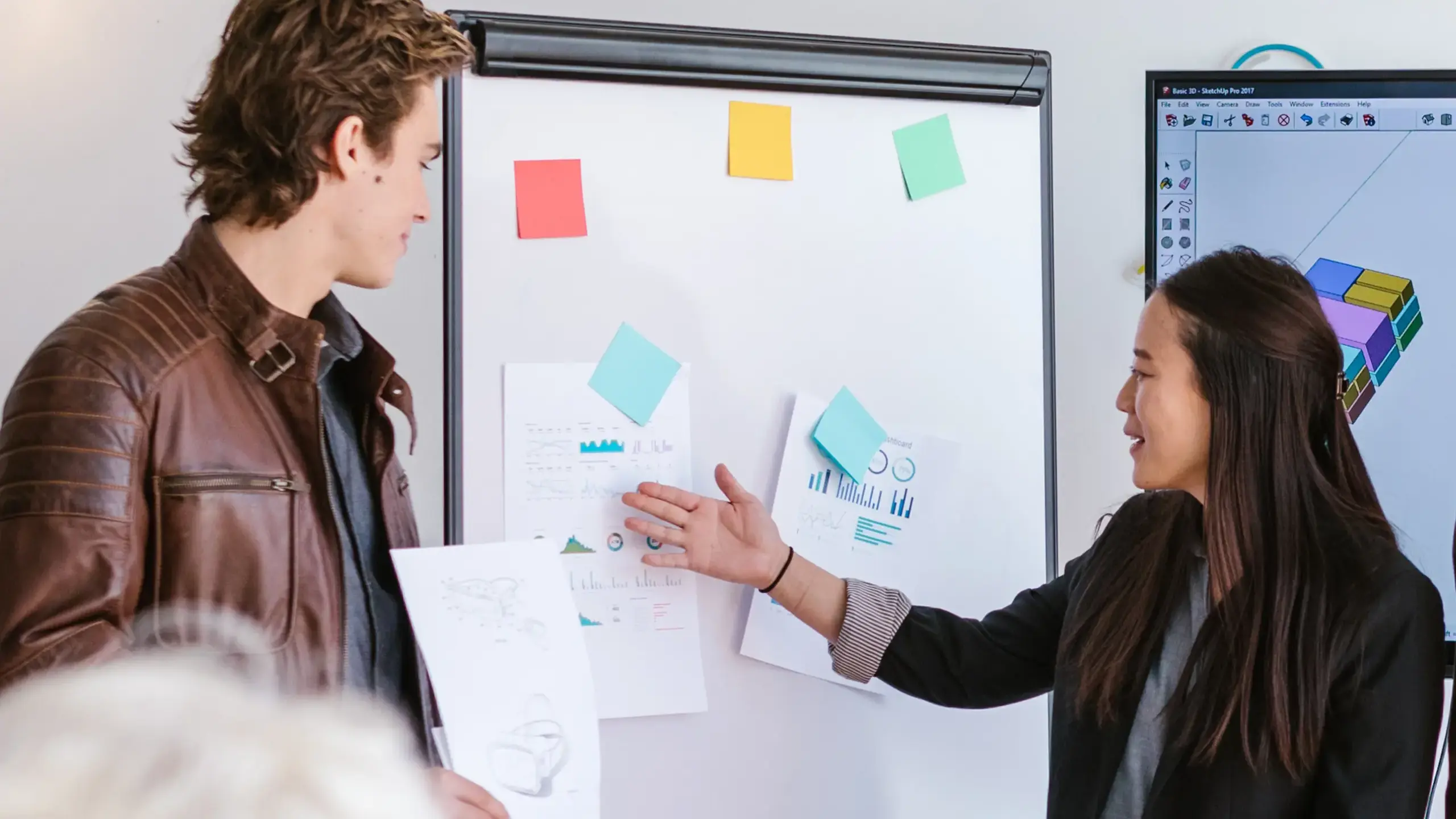 Teacher demonstrating to student using post-its attached to whiteboard