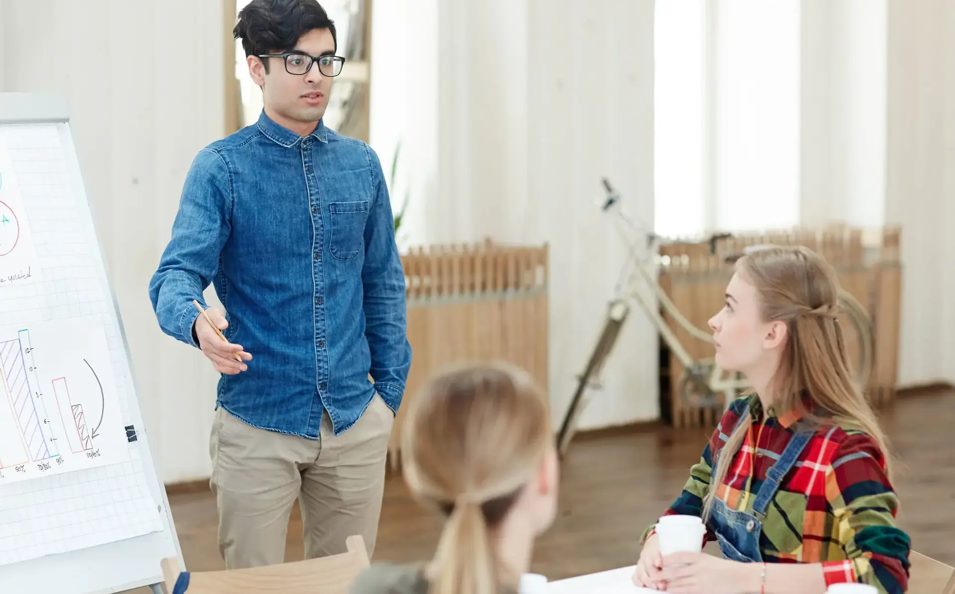 Teacher speaking to two students sitting at desk