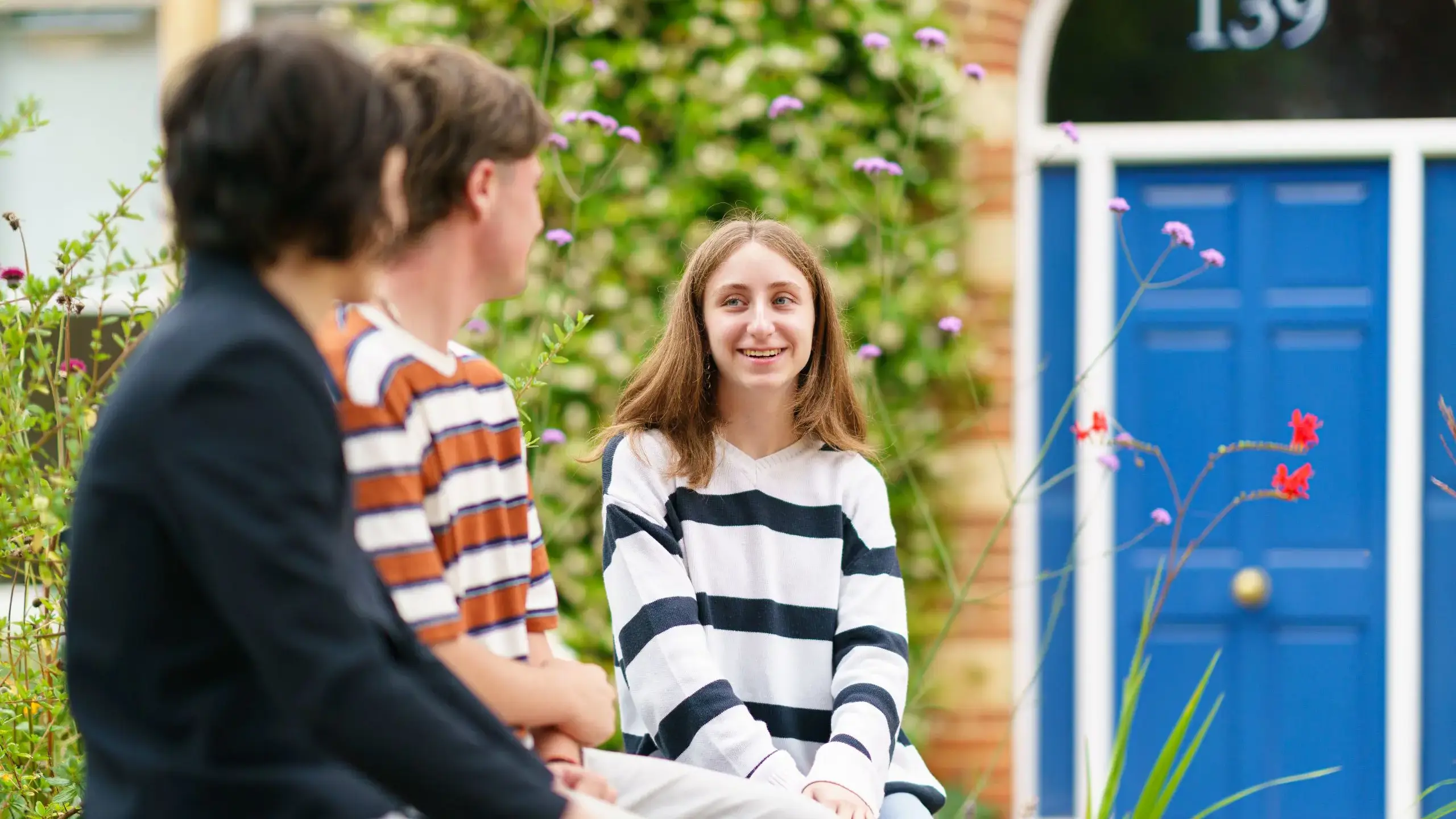 Smiling students sitting outside blue door
