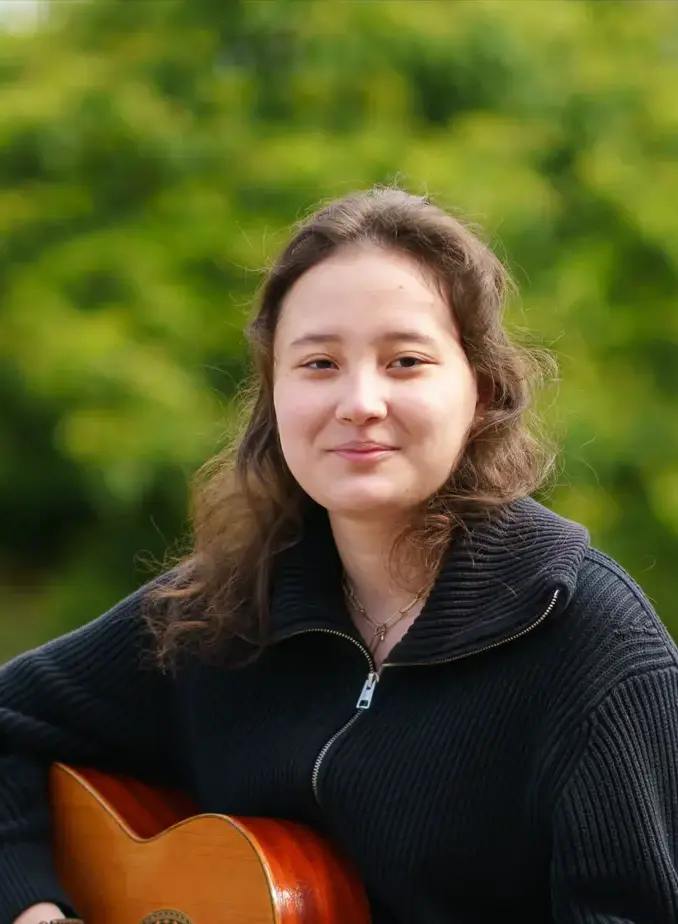 Female student with black sweater holding a guitar