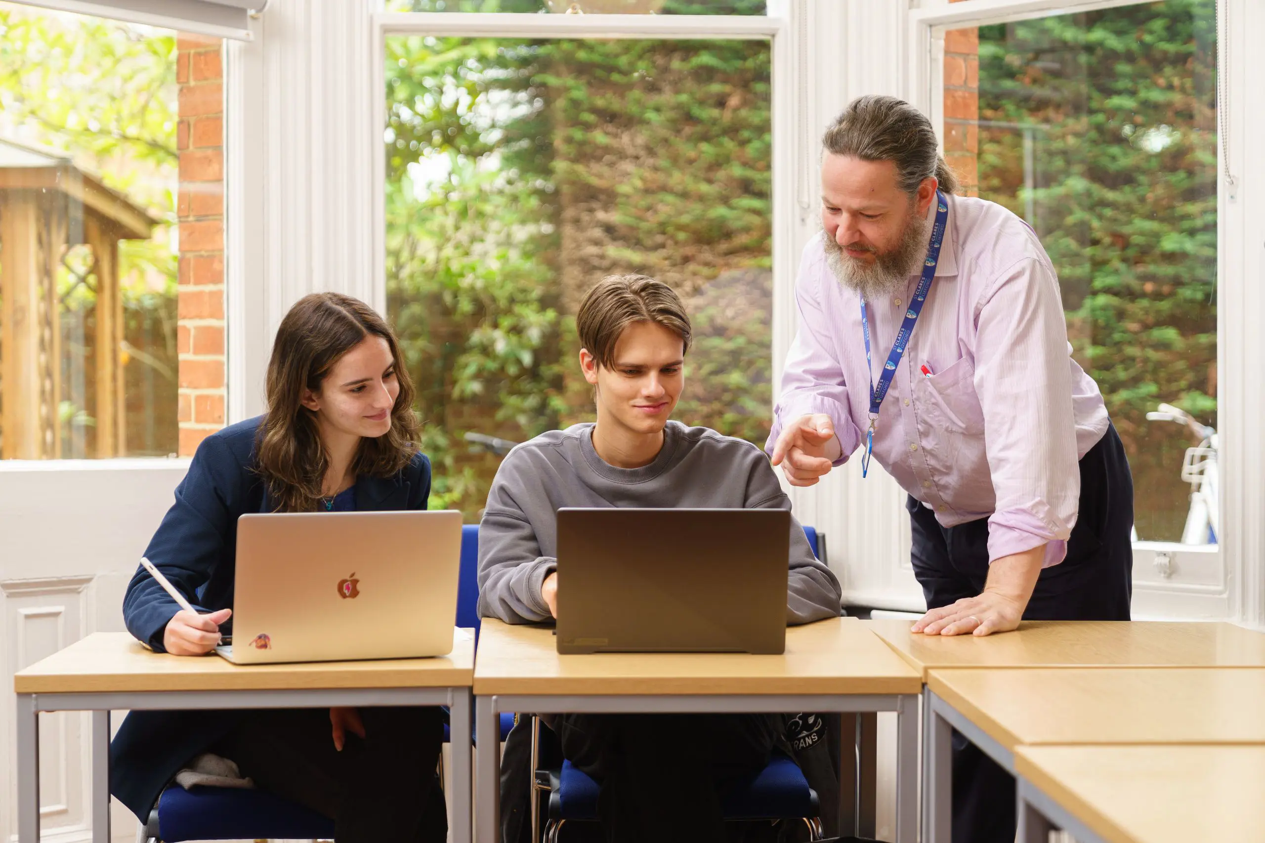 Male teacher advising two students in a classroom