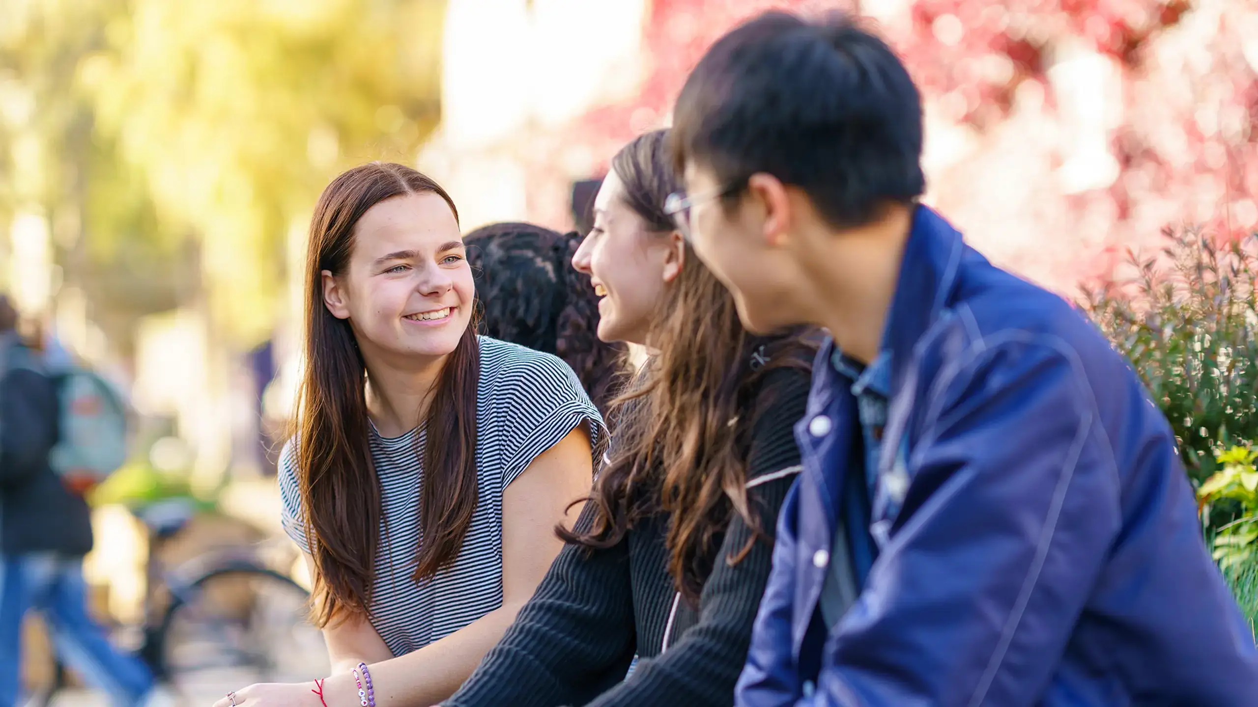 Group of students smiling and talking on campus in garden