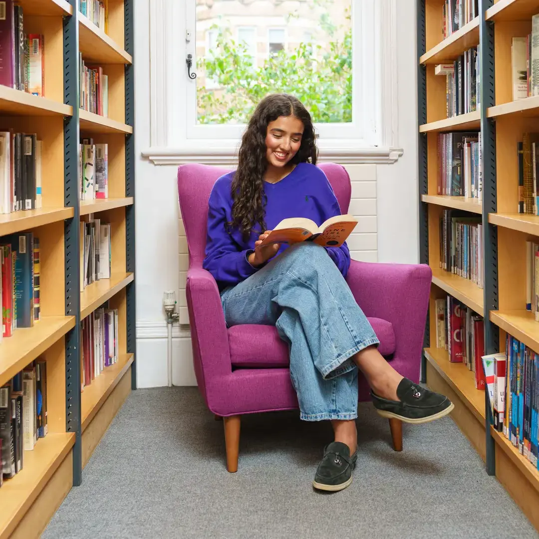 Female student sat reading a book in a library