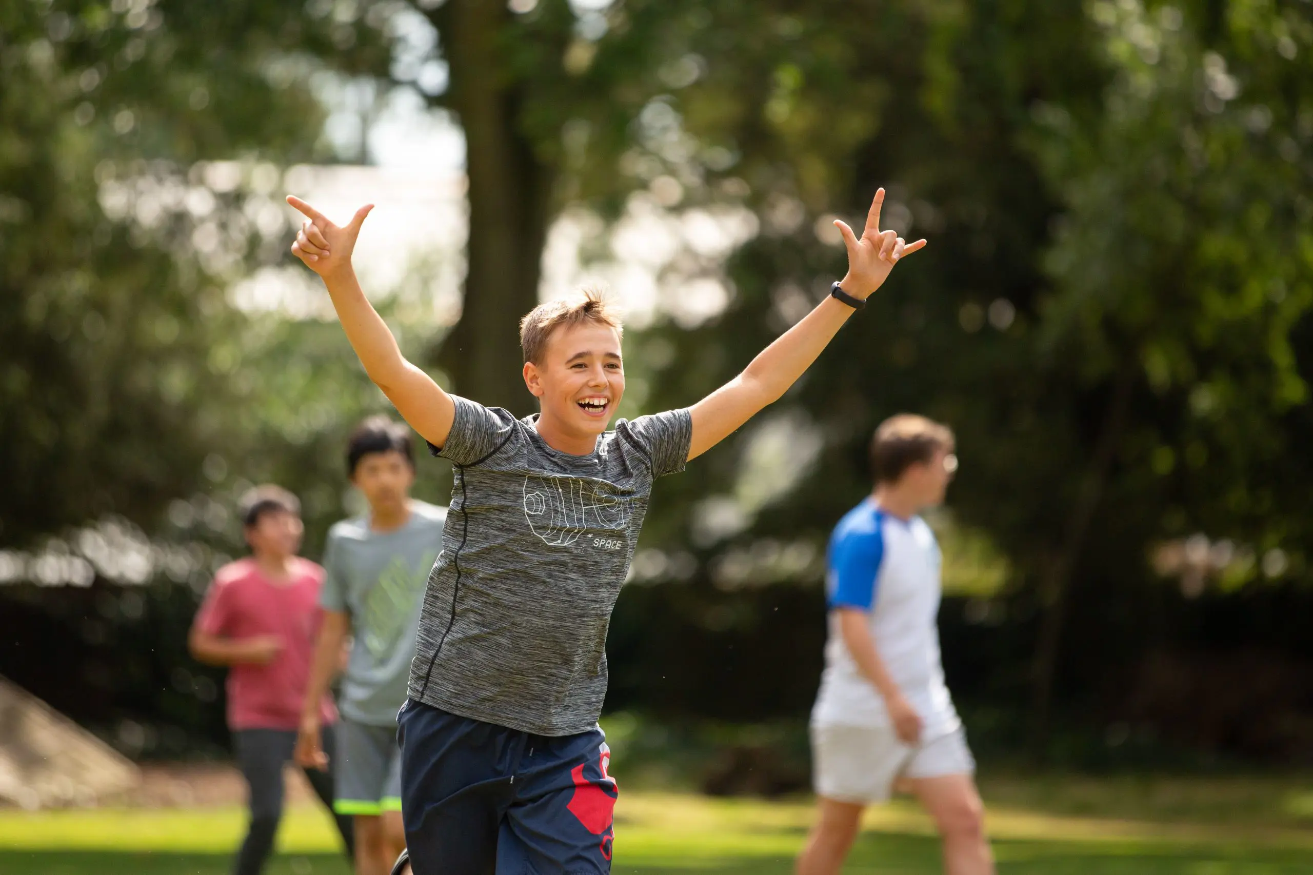 Boy running happy with arms in the air.
