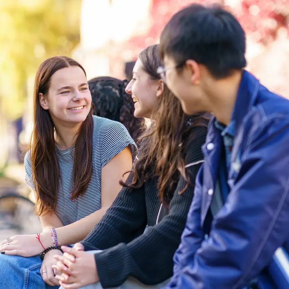 Students on bench outside smiling and talking
