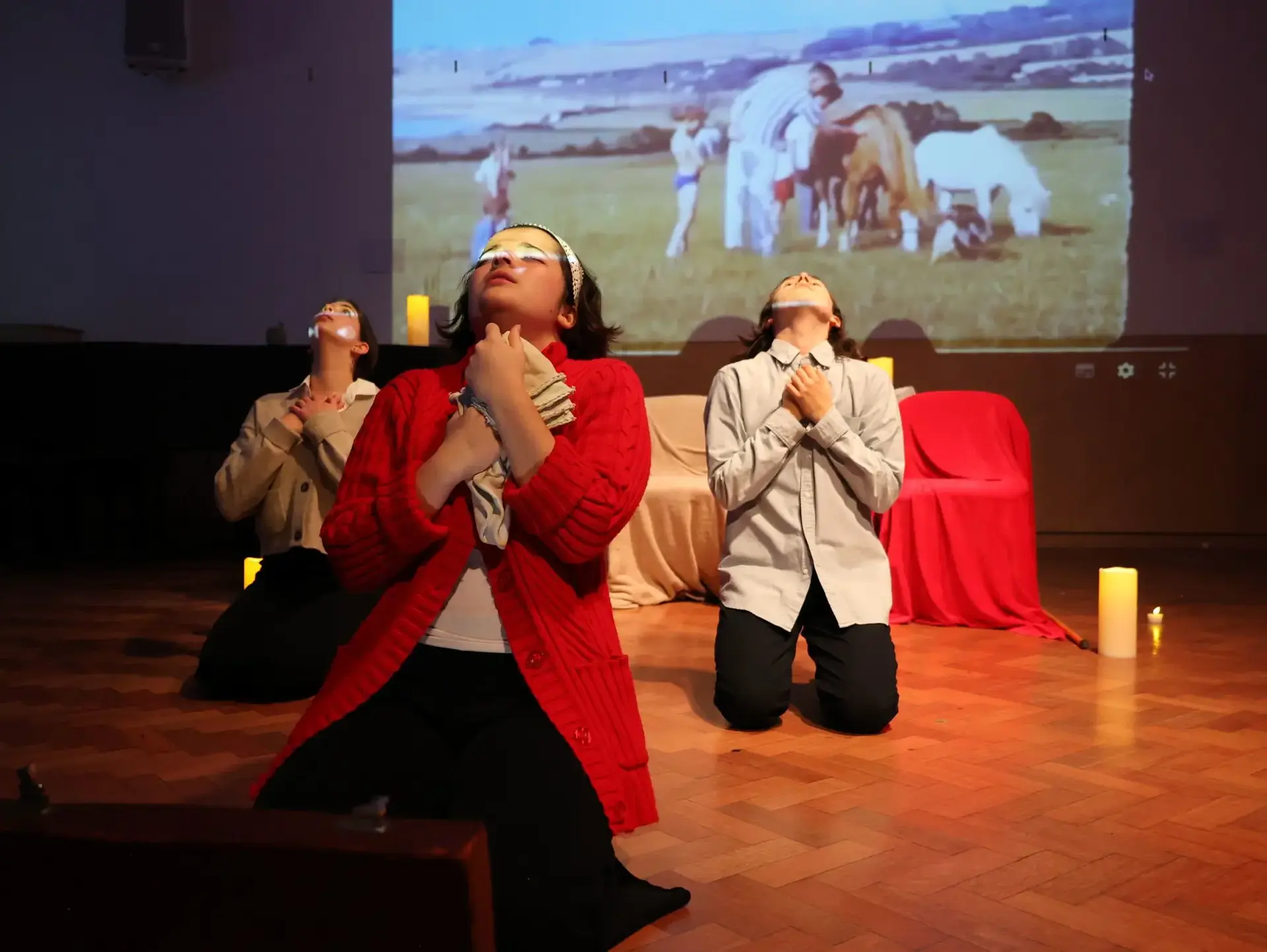 Students performing onstage, kneeling with faces upturned