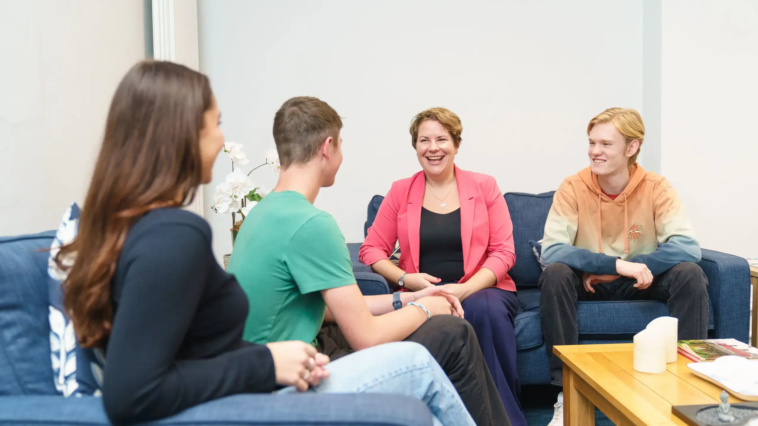 Teacher sitting with a group of students on a sofa having a a conversation